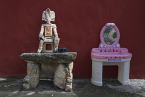Dualidad entre juguete y mesa de piedra con muñeco prehispánico ubicada en el albergue Oasis para personas con VIH en Yucatán